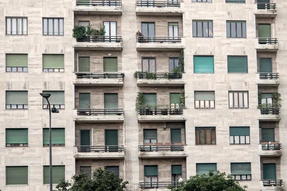 Residential apartment block with a stone facade, recessed balconies and lowered shutters