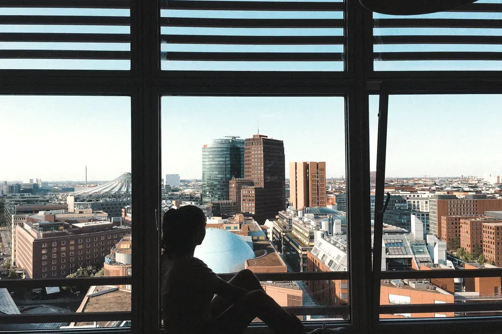 Silhouette of a person sitting at a floor-to-ceiling window with a view over Potsdamer Platz in Berlin