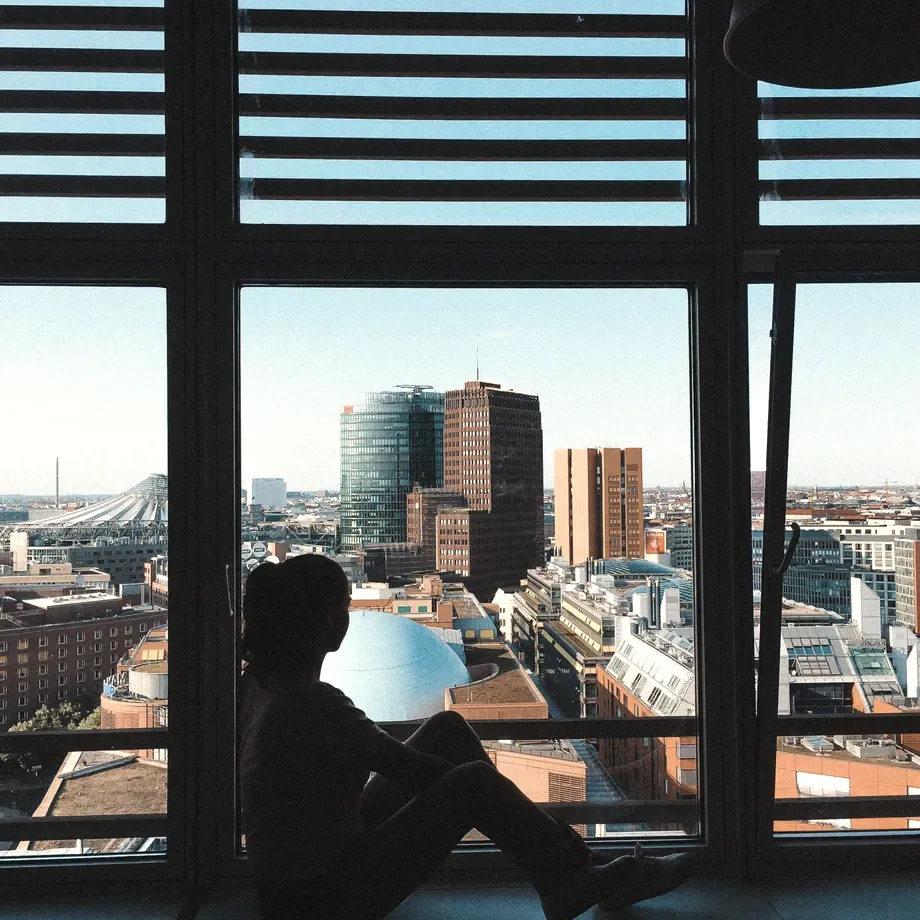 Silhouette of a person sitting at a floor-to-ceiling window with a view over Potsdamer Platz in Berlin