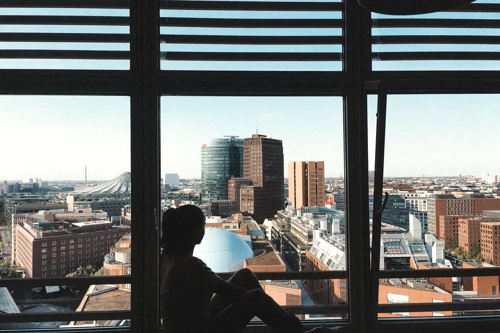 Silhouette of a person sitting at a floor-to-ceiling window with a view over Potsdamer Platz in Berlin