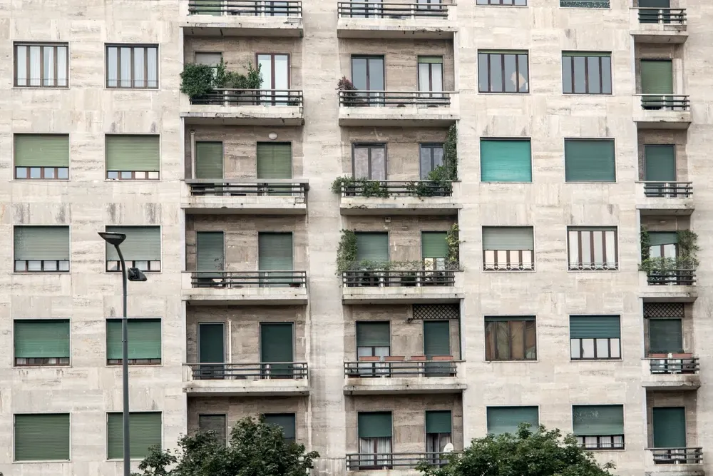 Residential apartment block with a stone facade, recessed balconies and lowered shutters