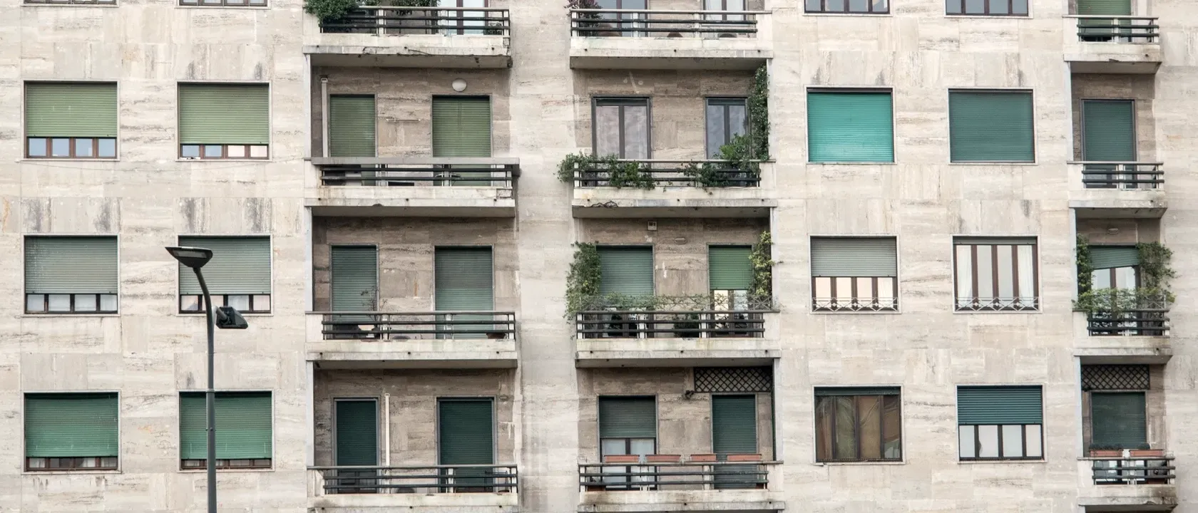 Residential apartment block with a stone facade, recessed balconies and lowered shutters