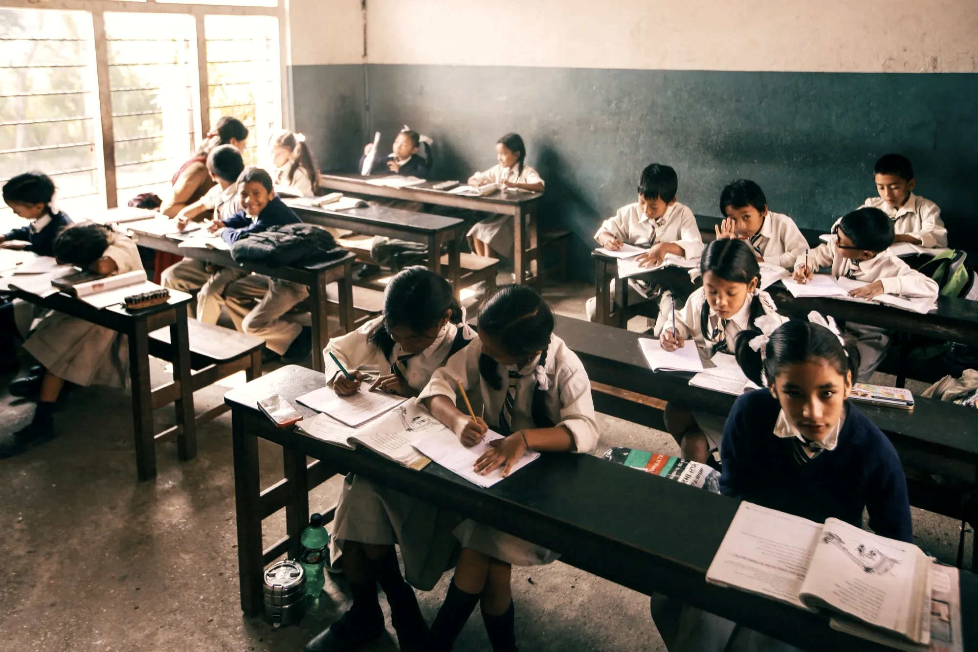 Elementary school children studying in a classroom, focusing intently on their work.